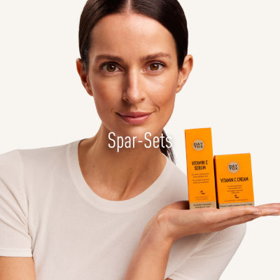 Lächelnde Frau präsentiert Pflegeprodukte mit Vitamin C auf der Hand